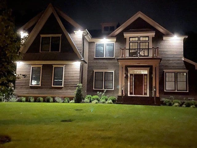 Modern home exterior illuminated at night with landscaped yard and inviting entrance.