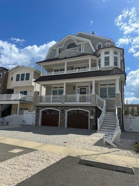 Luxury beachfront home with multiple balconies and stone accents under a blue sky.