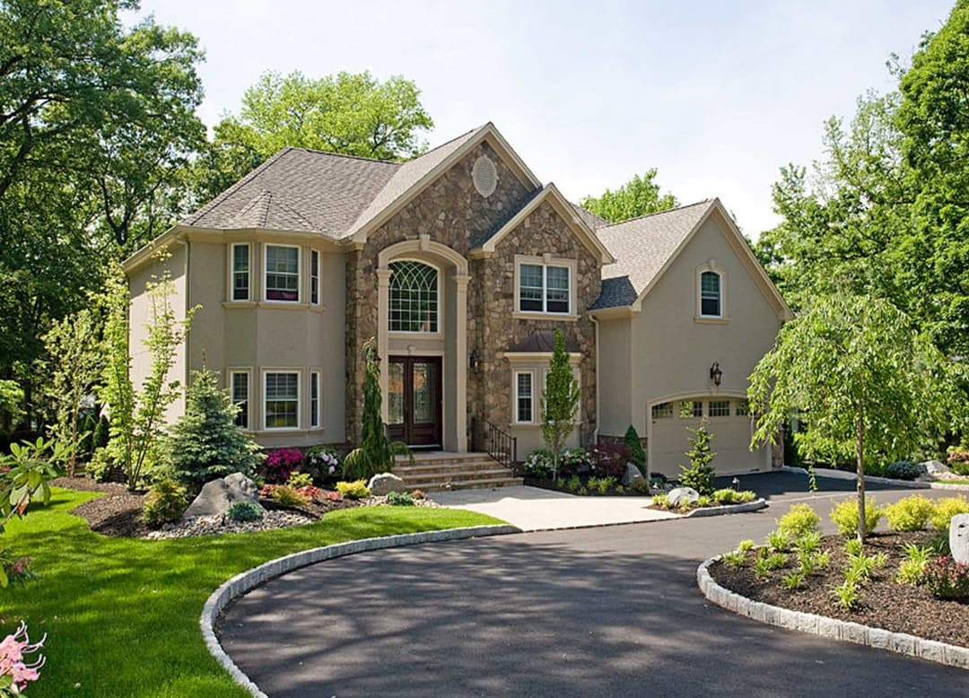 Elegant two-story home with stone accents, landscaped yard, and curved driveway.
