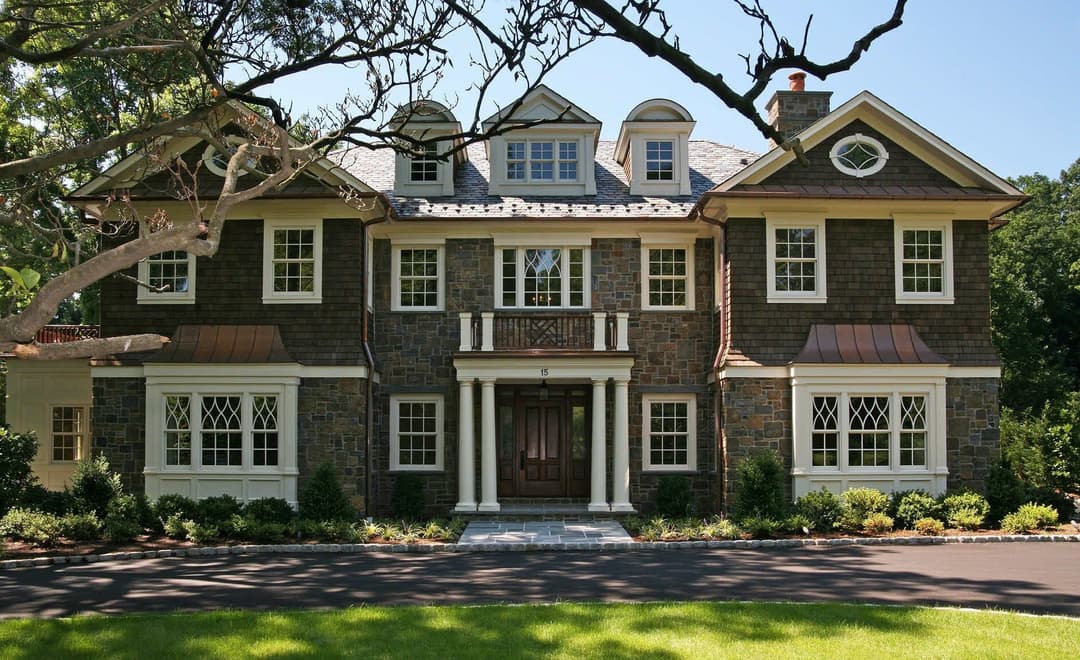 Elegant multi-story home with stone facade, wooden accents, and landscaped yard.