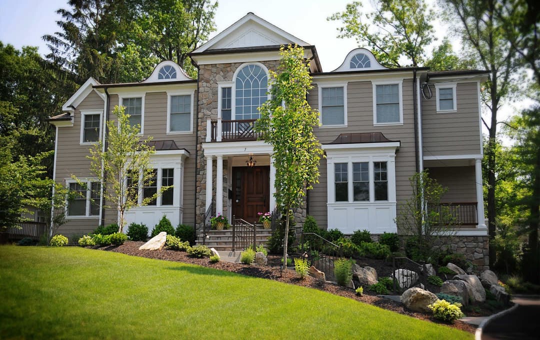 Elegant two-story home with stone accents, landscaped yard, and welcoming entrance.