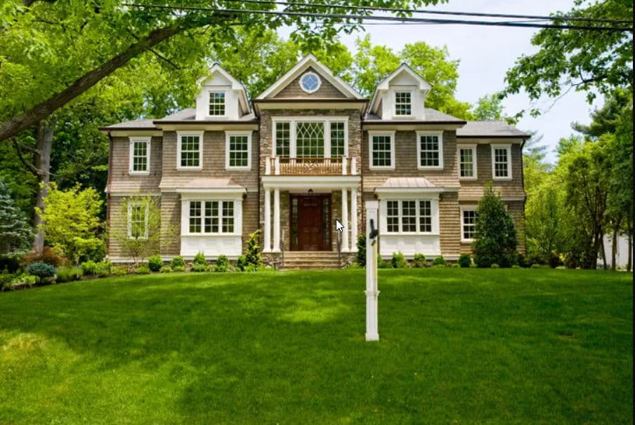 Elegant two-story house with a manicured lawn, large windows, and a welcoming front porch.