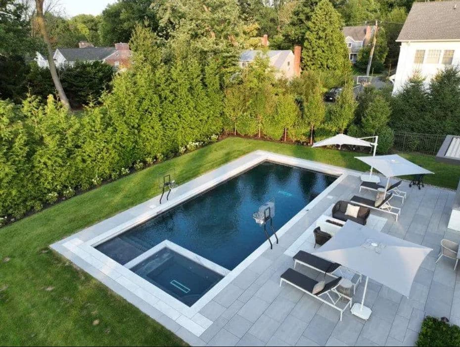 Luxury backyard with a modern swimming pool, lounging chairs, and shaded umbrellas.