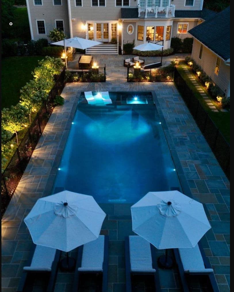 Aerial view of a luxurious backyard pool with lounge chairs and umbrellas at a stylish home.
