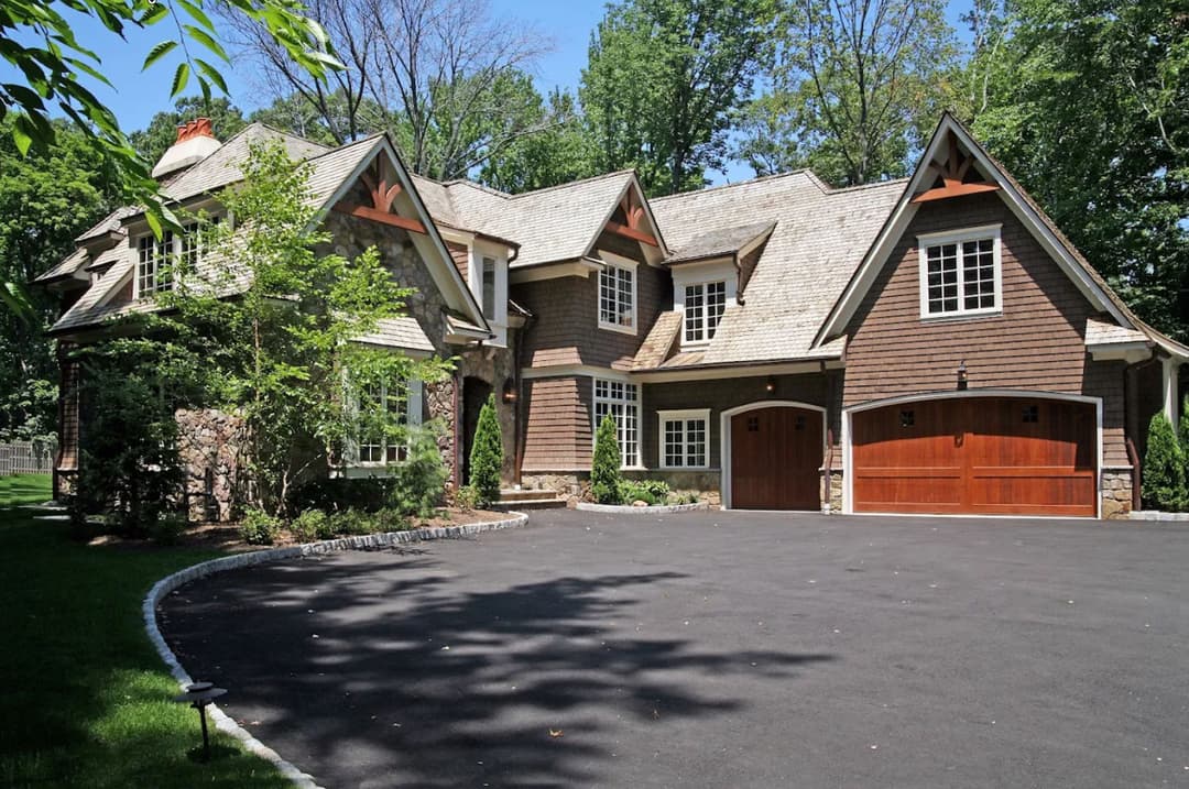 Modern two-story home with a stone facade, wooden accents, and landscaped yard.