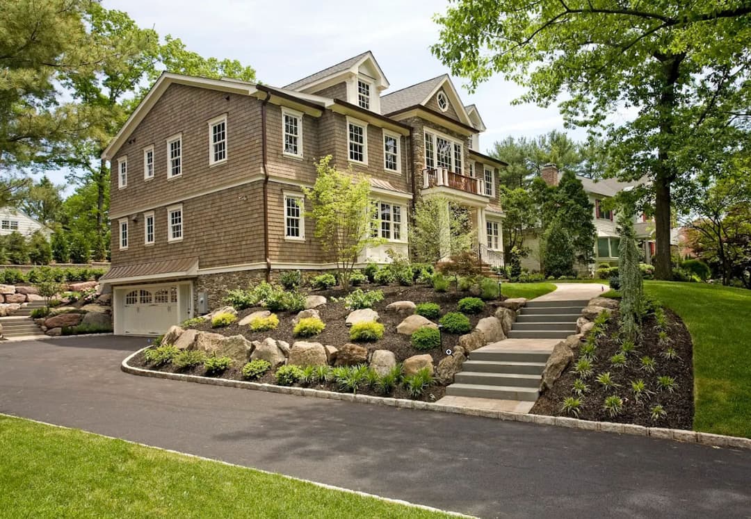 Charming two-story house with landscaped yard and stone pathway on a sunny day.