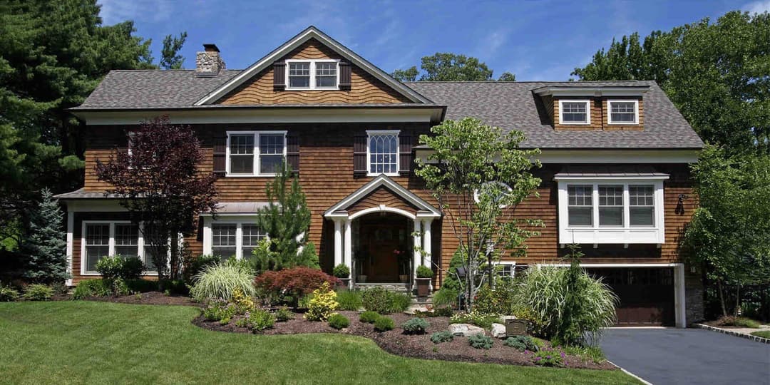 Beautiful wooden suburban home with landscaped garden and clear blue sky.