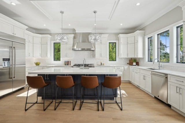 Modern kitchen with white cabinetry, a large island with bar stools, and elegant pendant lighting.