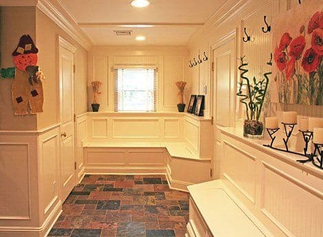 Cozy entrance hall with seating, flower artwork, and stone tile flooring.