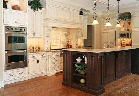 Elegant kitchen with cream cabinets, dark wood island, modern appliances, and warm lighting.