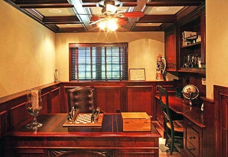 Home office with wooden decor, chess set, globe, and a cozy ambiance featuring a ceiling fan.