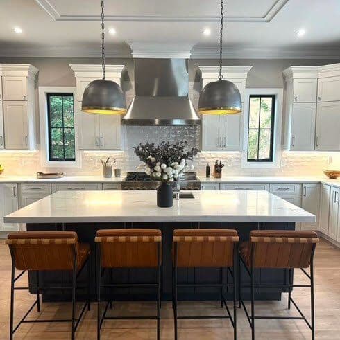 Modern kitchen with white cabinetry, sleek island, bar stools, and stylish pendant lighting.