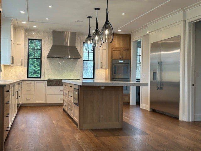 Modern kitchen with wooden cabinets, large island, stainless steel appliances, and pendant lighting.