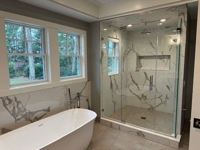 Modern bathroom featuring a freestanding bathtub and glass shower with marble accents.