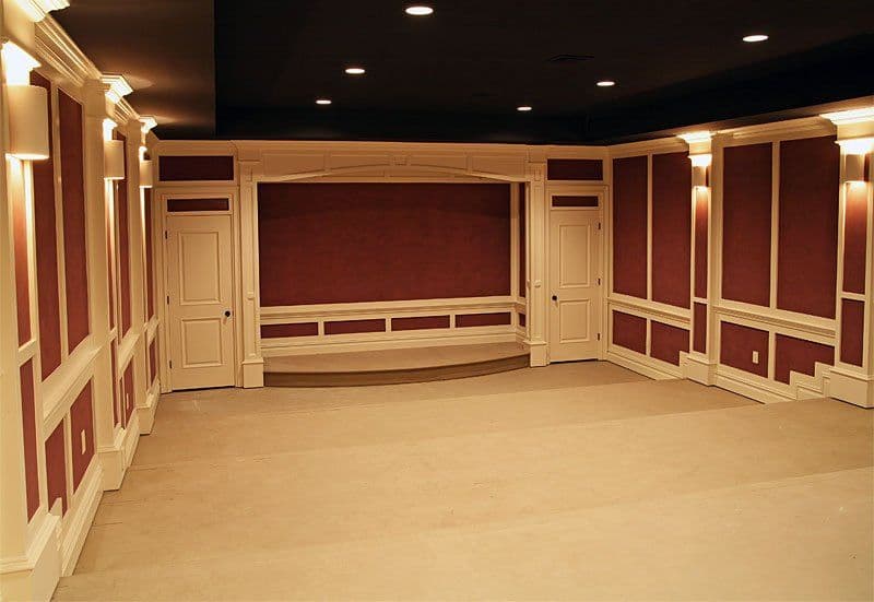 Elegant, empty theater room with red walls, white paneling, and ambient lighting.