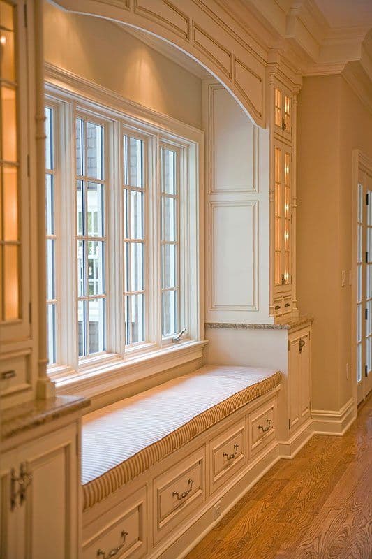 Elegant bay window with built-in seating, framed by custom cabinetry and warm lighting.