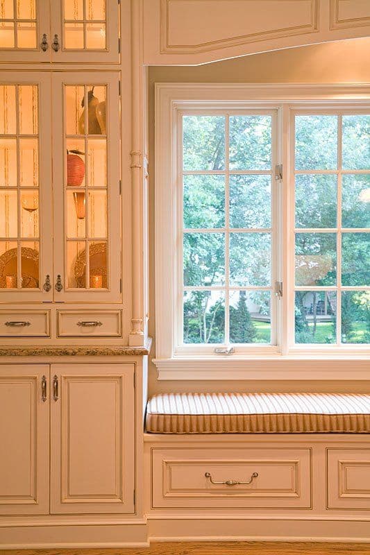 Elegant kitchen with white cabinets, granite countertop, and a cozy window seat. Natural light streaming in.