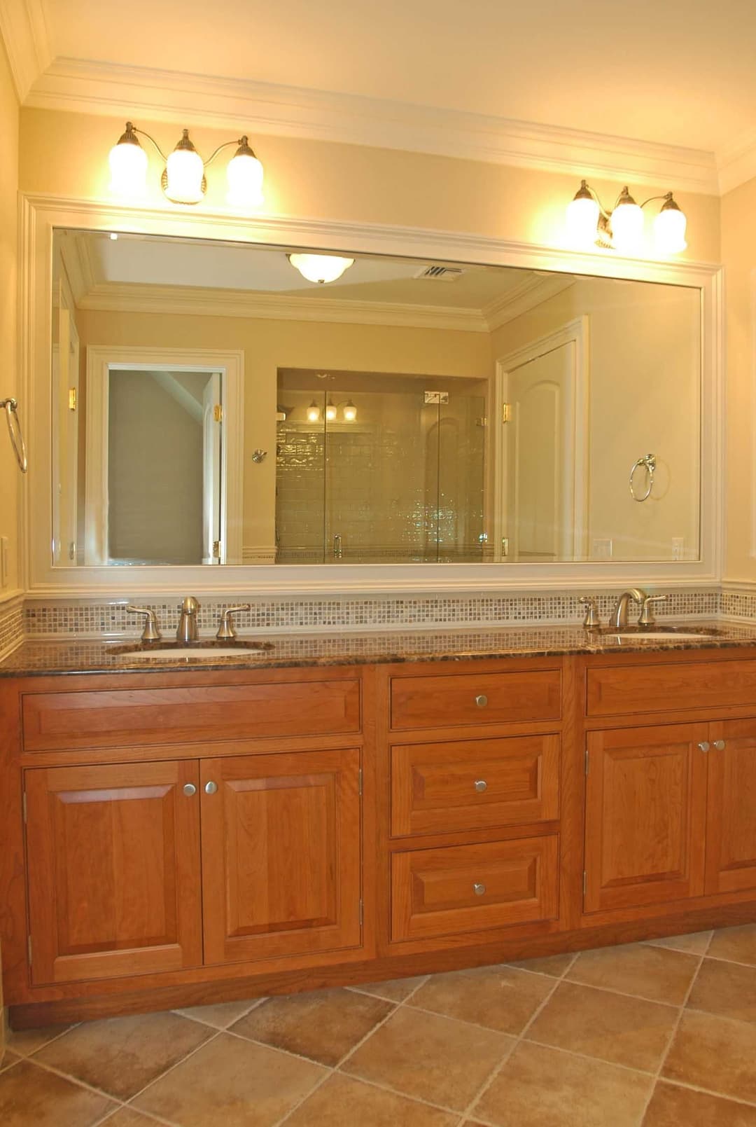 Elegant bathroom with wooden cabinetry, double sinks, and spacious shower area.
