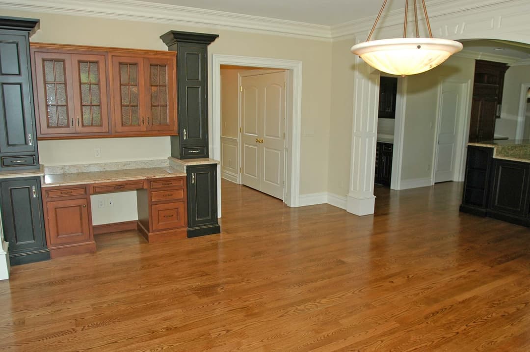 Spacious kitchen interior with wooden cabinets, granite countertops, and hardwood flooring.