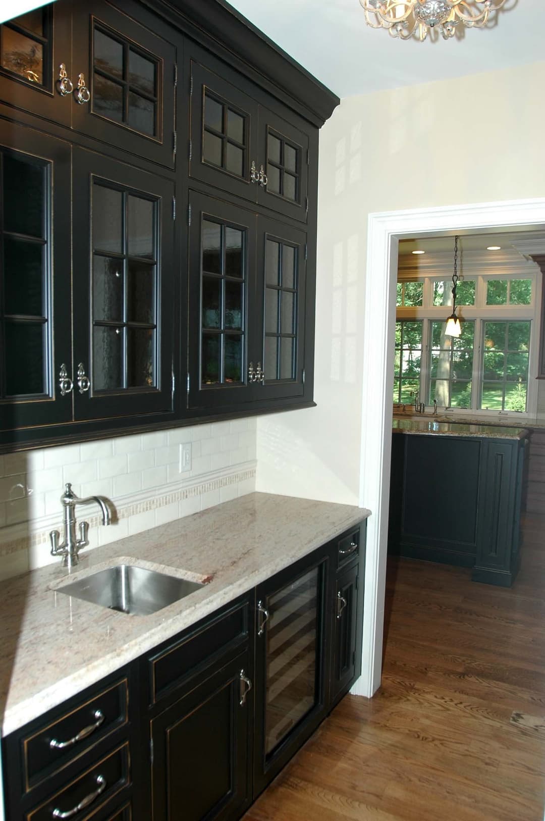 Modern kitchen with black cabinets, granite countertop, and wine cooler in stylish design.