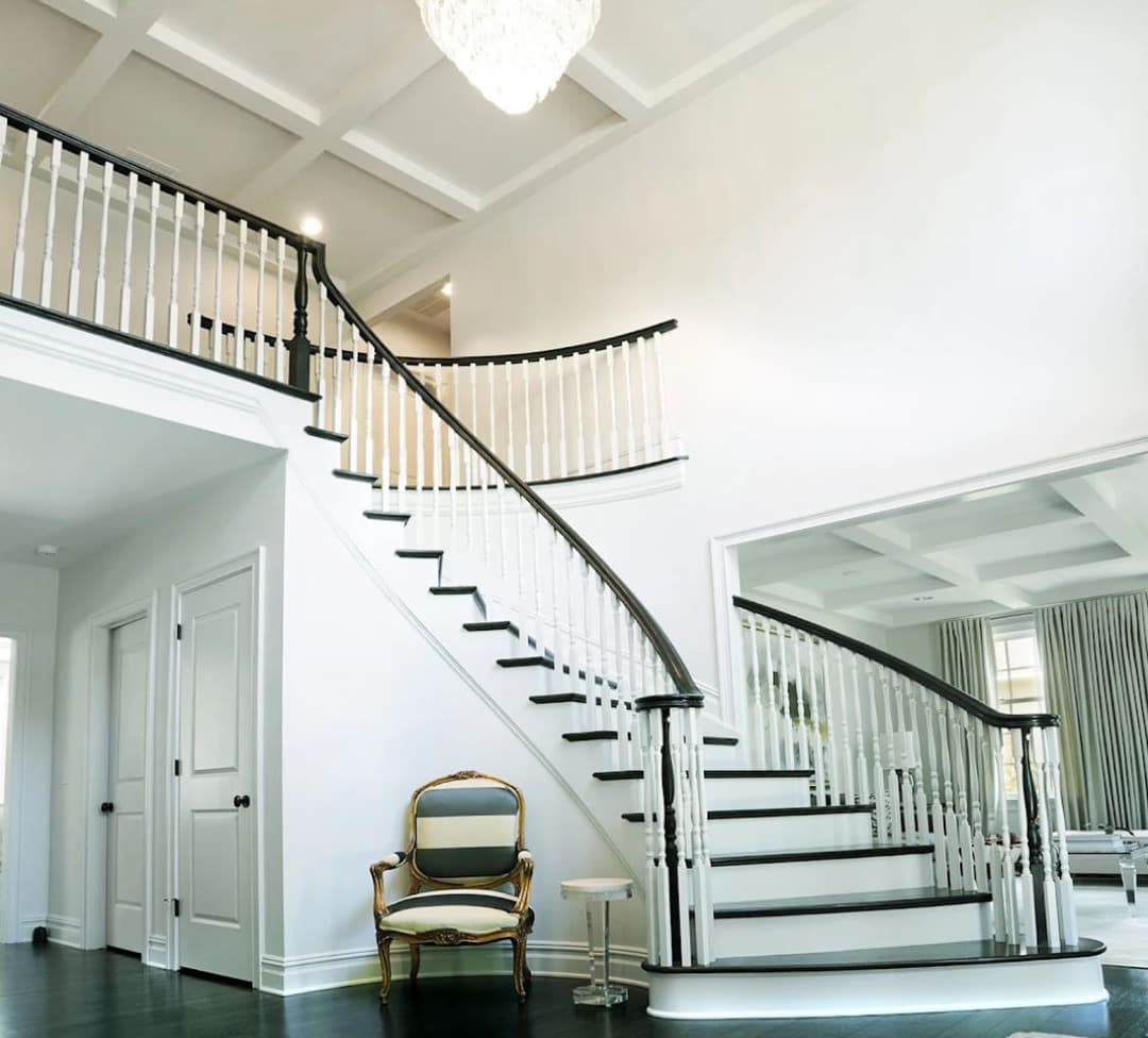 Elegant curved staircase in a modern home, featuring white balusters and dark wooden steps.