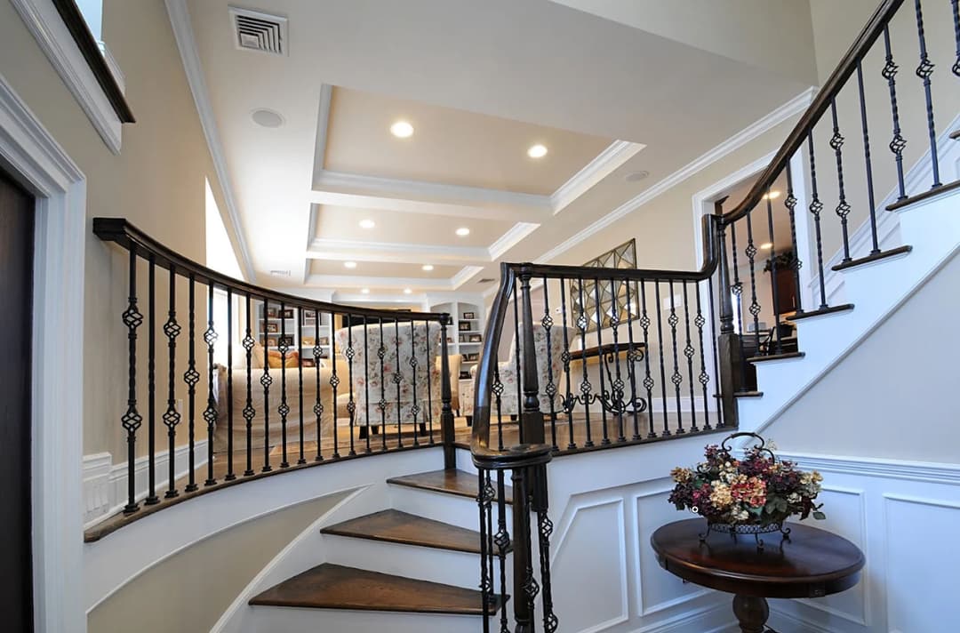 Elegant curved staircase with decorative railing leading to a stylish living area.