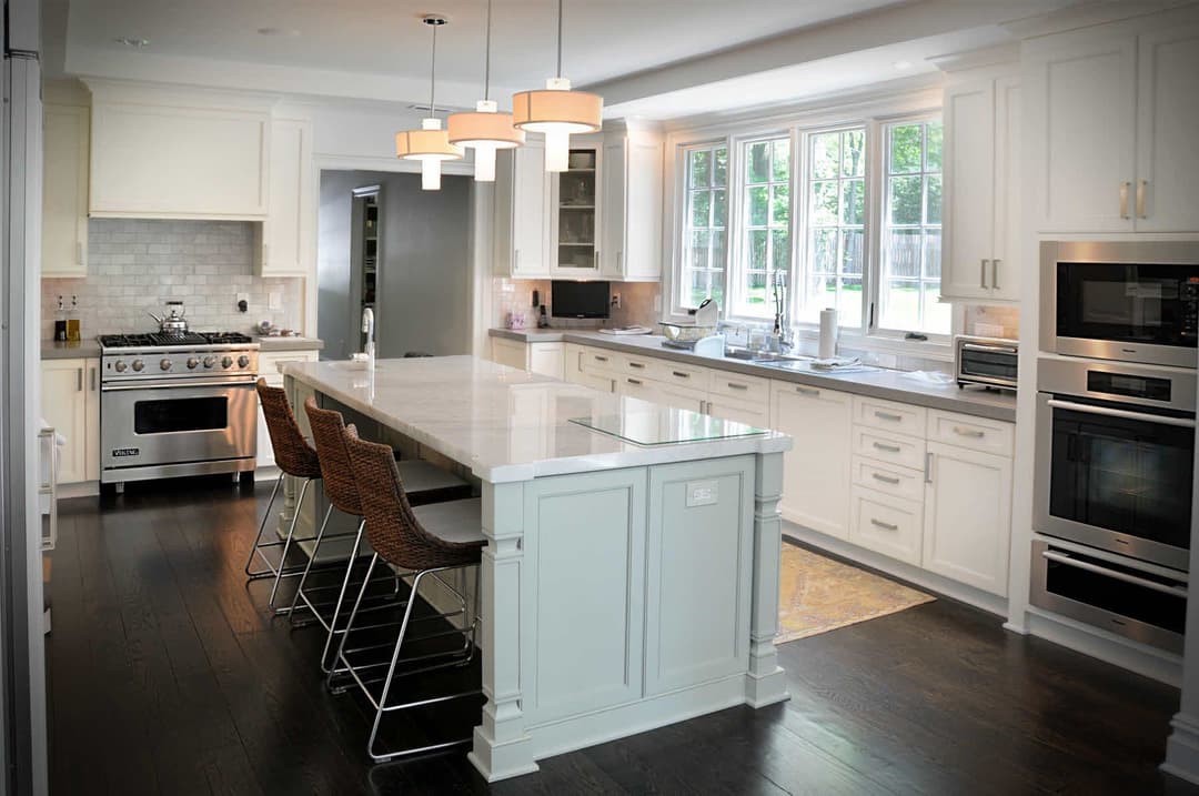 Modern kitchen with white cabinets, a large island, stainless steel appliances, and pendant lighting.