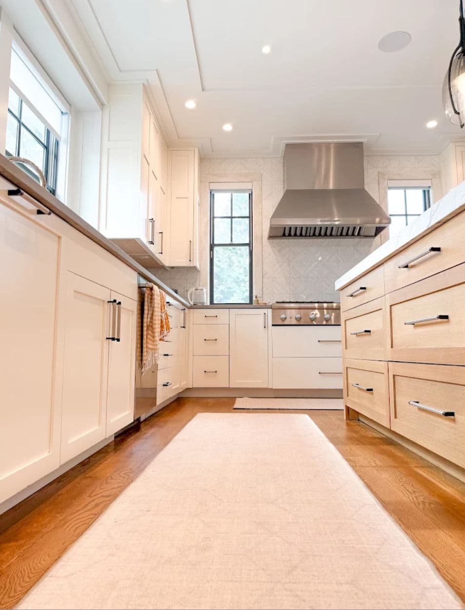 Modern kitchen design featuring light cabinetry, stainless steel appliances, and hardwood flooring.