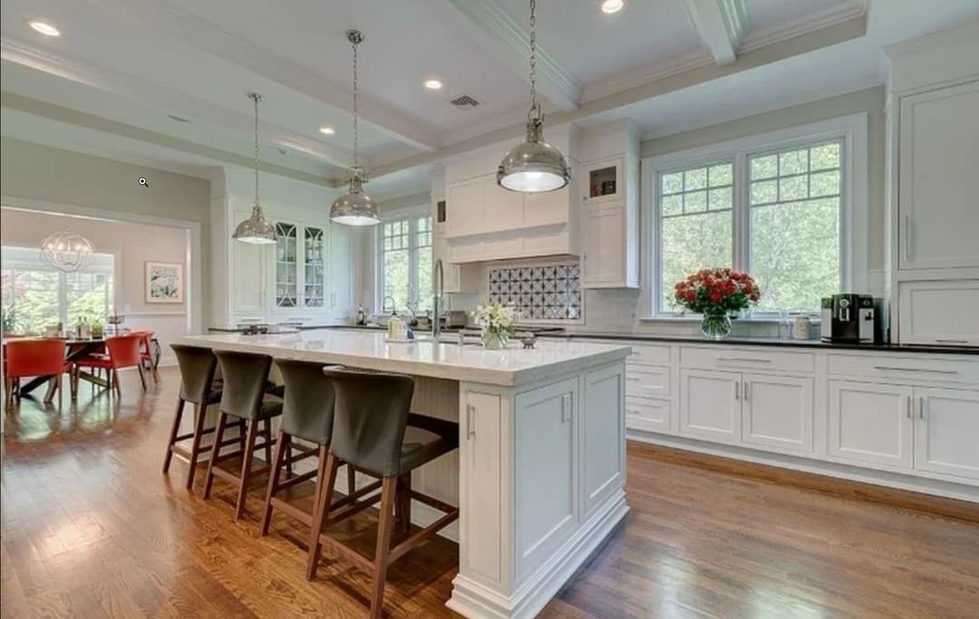 Modern kitchen with white cabinetry, granite island, and stylish pendant lights.