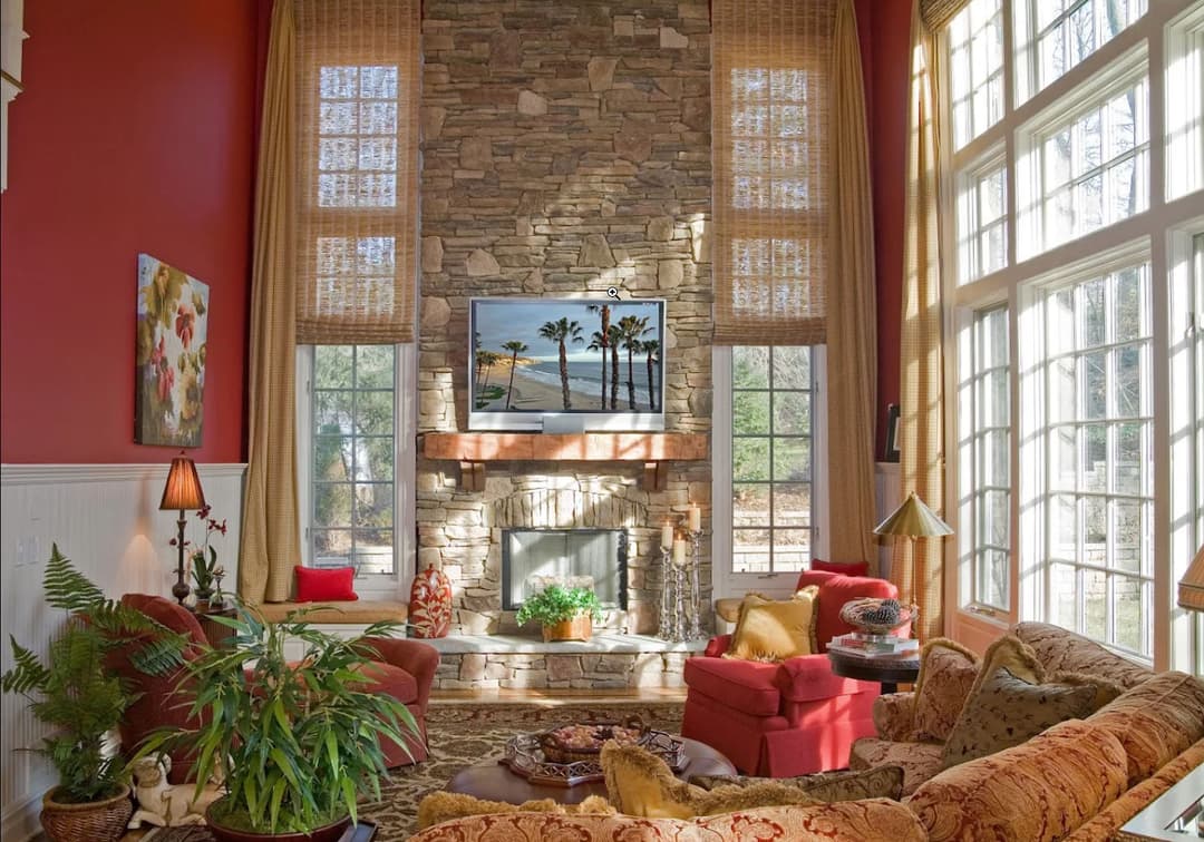 Cozy living room with stone fireplace, large windows, and vibrant decor in warm tones.