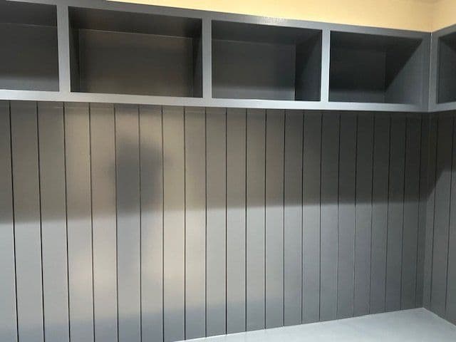 Modern gray storage wall with open shelves and vertical paneling design.